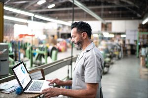 Ein Mann arbeitet an einem Labtop abgetrennt von der Produktion