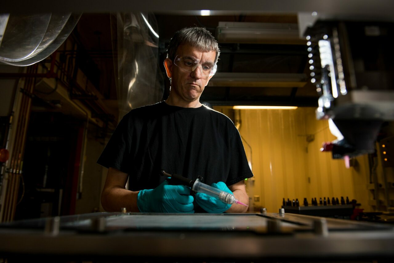 man with protective goggles and a syringe in his hand