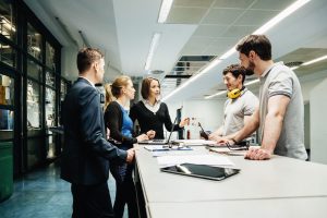 5 people standing around a table in an office room