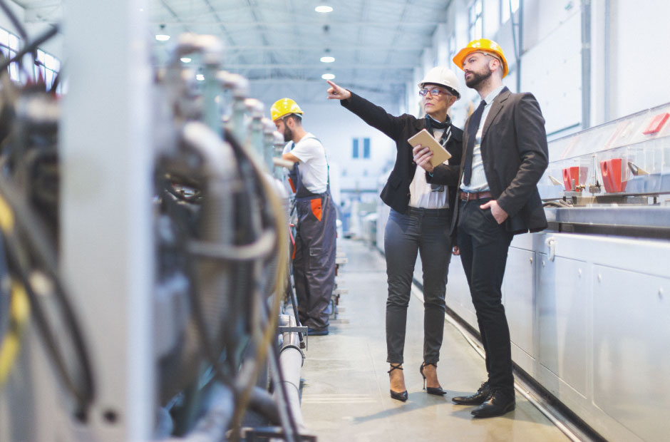 Man and woman with safety helmet standing in a production.